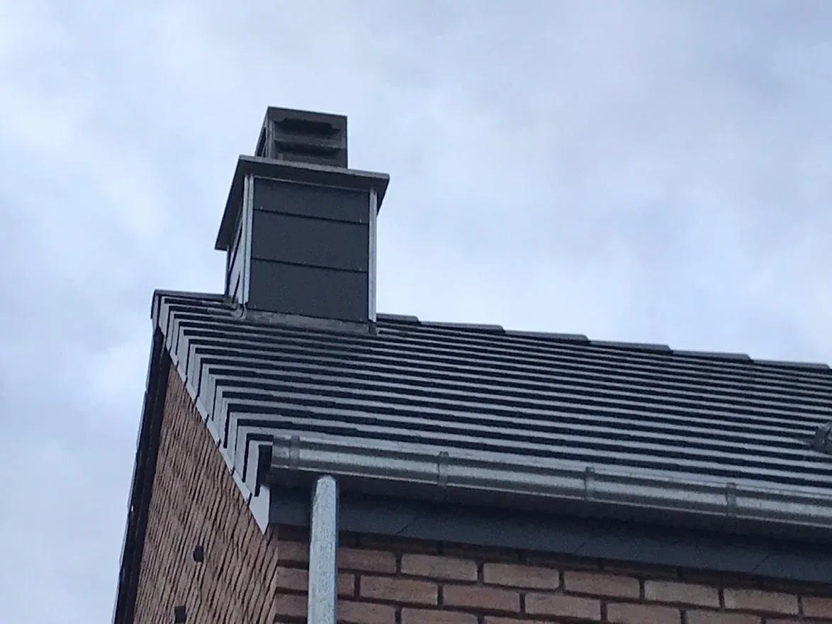 Cheminée zinguée et gouttière sur une toiture en ardoises